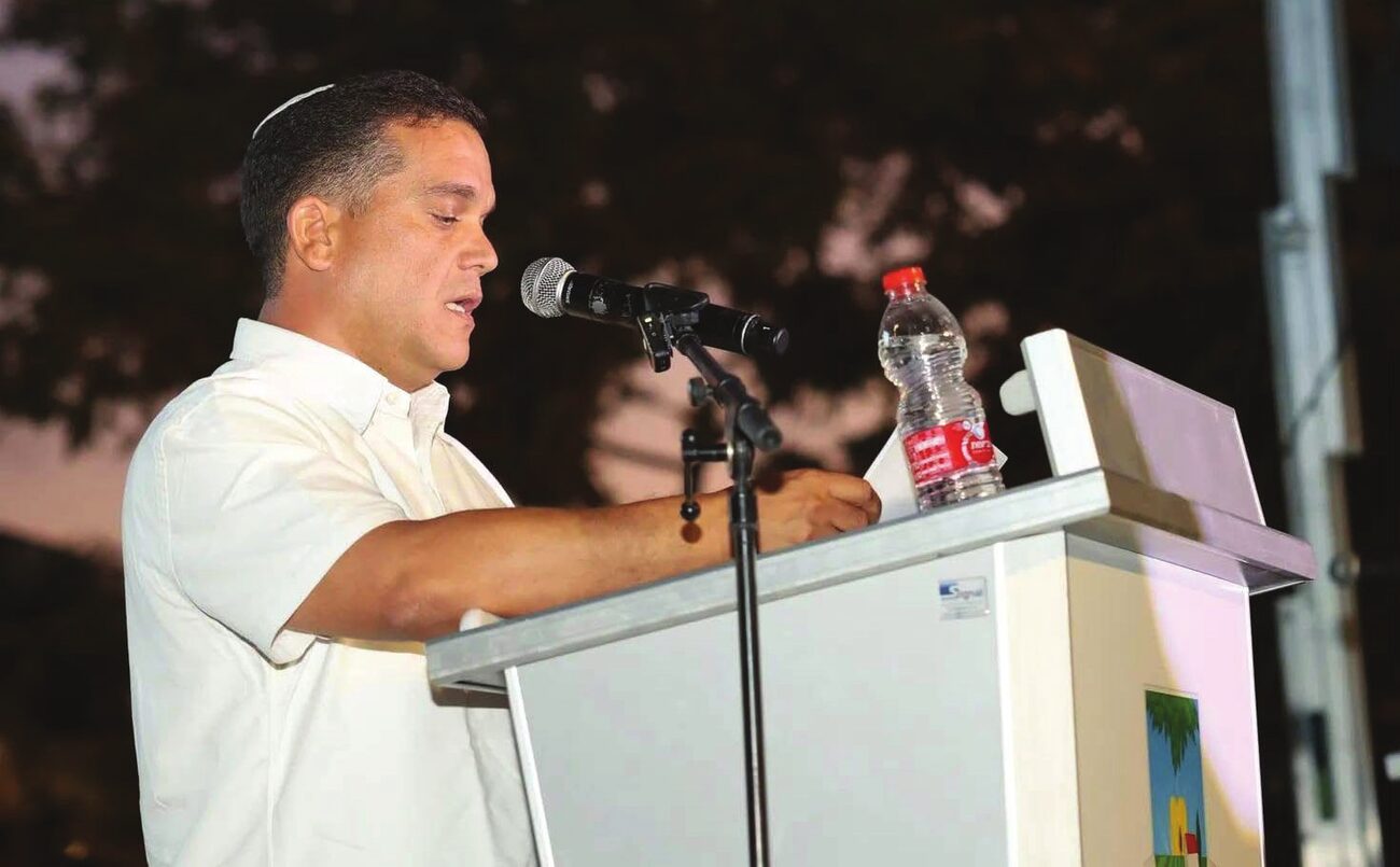 יוני ממו נואם על במה באירוע קהילתי